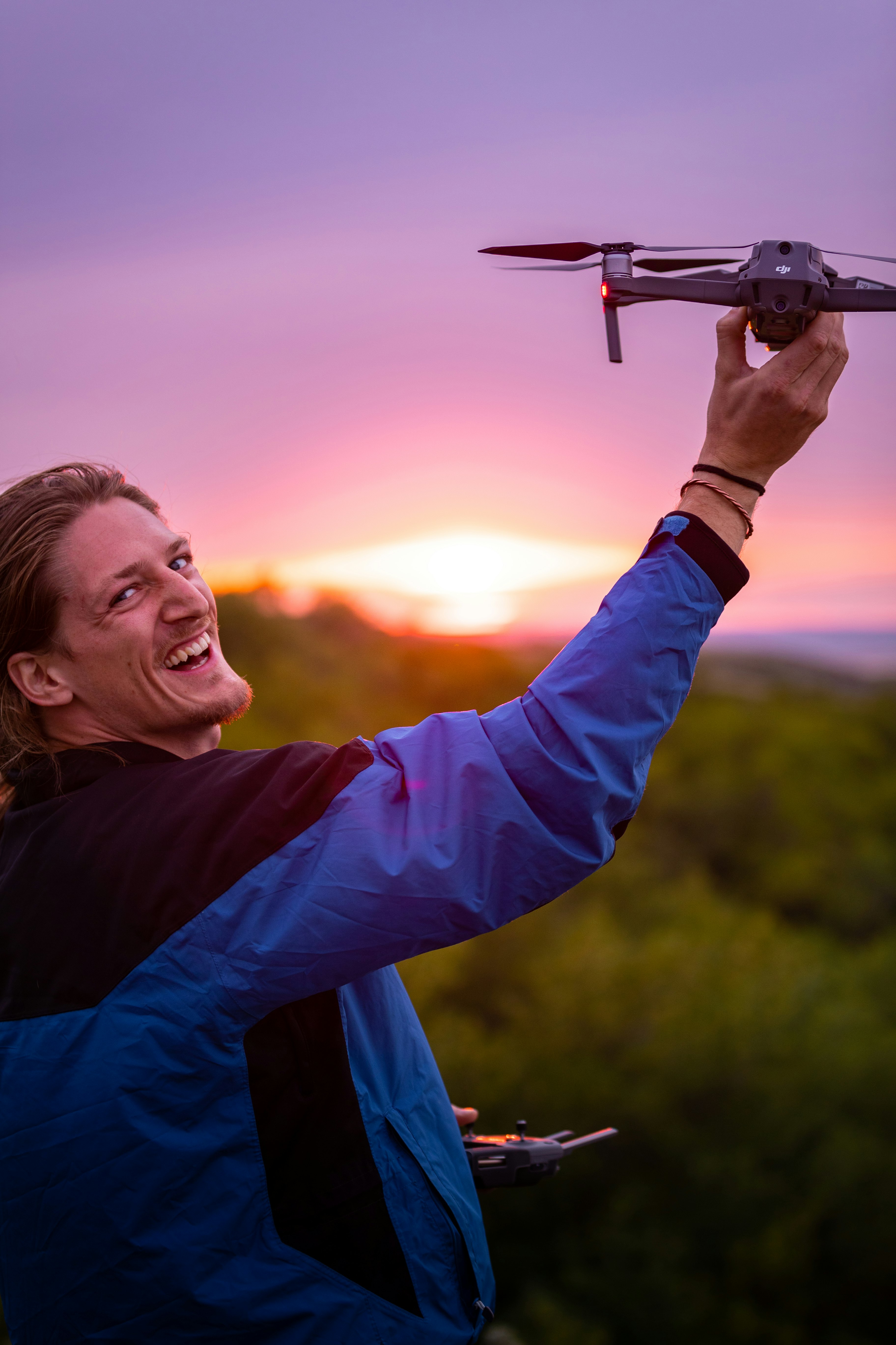 smiling woman in blue long sleeve shirt holding black and gray drone